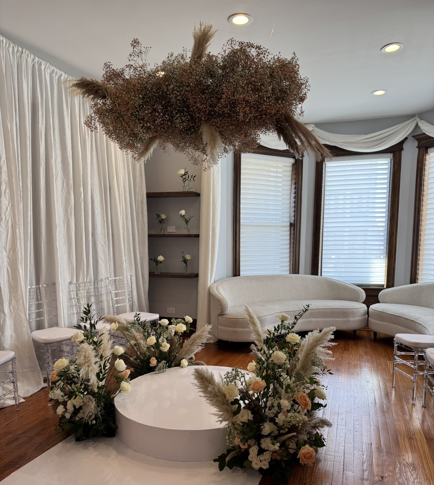 Ceremony space with hanging pampas grass installation and white floral arrangements